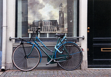 604310 Afbeelding van een blauwe damesfiets voor de etalage van het pand Oudegracht 18 te Utrecht, met achter het ...